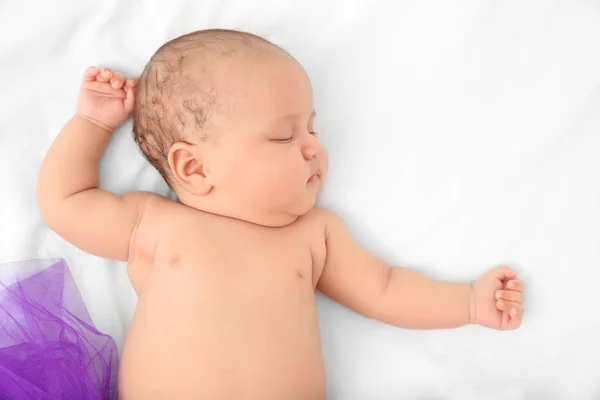 Cute baby in purple skirt sleeping on bed — Stock Photo, Image