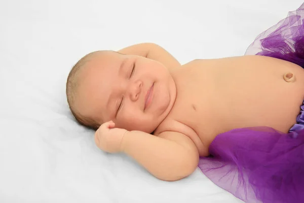 Bebê bonito em saia roxa dormindo na cama — Fotografia de Stock