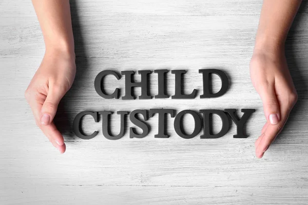 Human hands and words CHILD CUSTODY on wooden background, top view — Stock Photo, Image