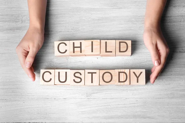 Manos y cubos femeninos con texto CHILD CUSTODY sobre fondo de madera, vista superior —  Fotos de Stock