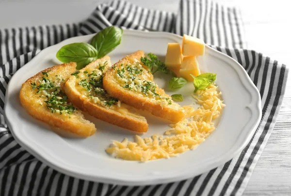 Teller mit leckerem Knoblauch französische Brotscheiben und gestreifte Serviette — Stockfoto