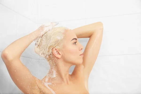 Beautiful young woman washing head in shower — Stockfoto