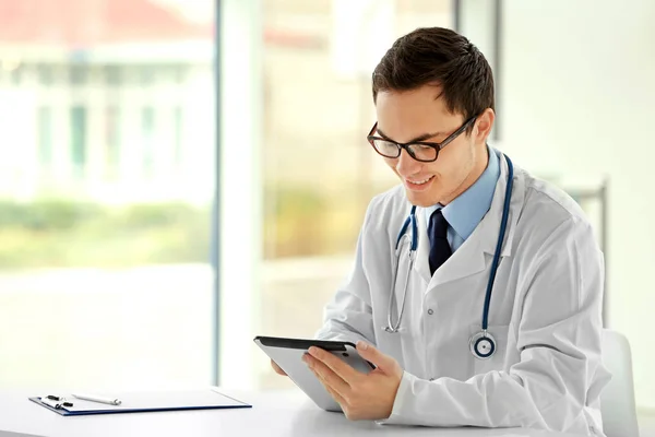 Jovem médico do sexo masculino com tablet no escritório — Fotografia de Stock