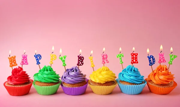 Verjaardag cupcakes met kaarsen op kleur achtergrond — Stockfoto