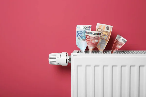 Savings concept. Money and heating radiator with temperature regulator on pink background — Stock Photo, Image