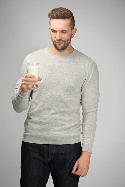 Jeune homme avec un verre de lait frais sur fond gris — Photo