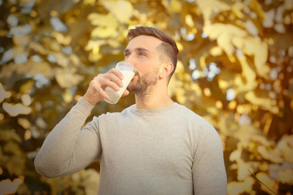 Joven con vaso de leche fresca al aire libre — Foto de Stock