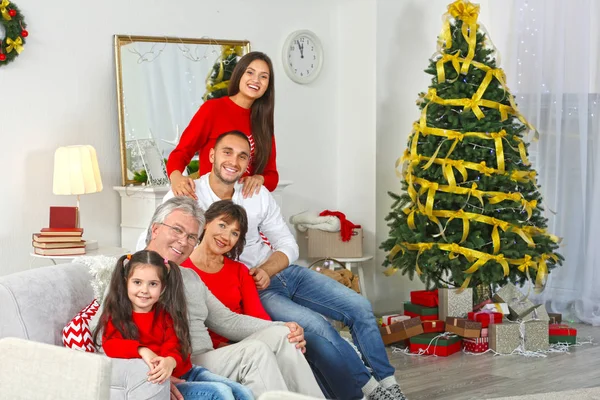 Happy family sitting on sofa in living room decorated for Christmas — Stock Photo, Image