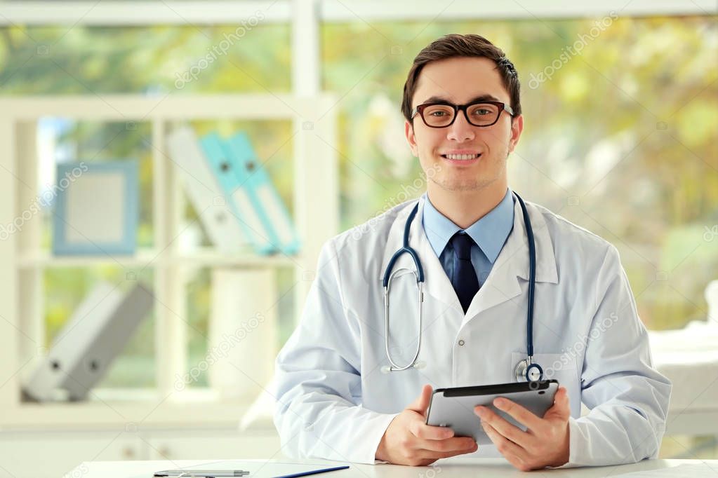 Young male doctor with tablet in office