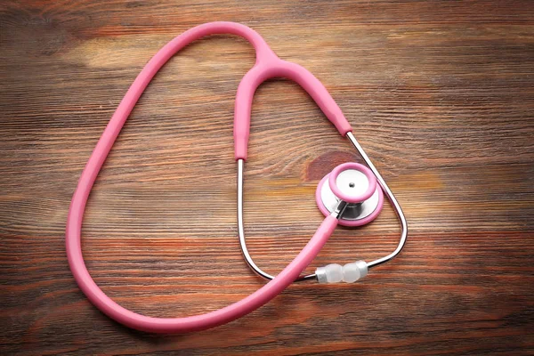 Vaaleanpunainen stetoskooppi puinen tausta — kuvapankkivalokuva