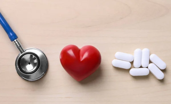 Corazón rojo con estetoscopio y pastillas —  Fotos de Stock