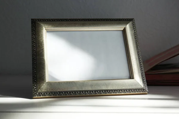 Vintage frame on wooden surface against dark wall — Stock Photo, Image