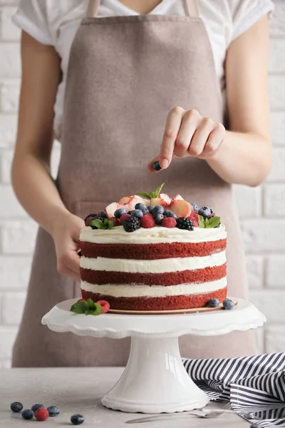 Женщина украшает вкусный торт — стоковое фото