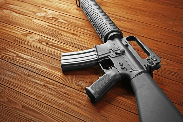 Útočná puška na dřevěný stůl — Stock fotografie