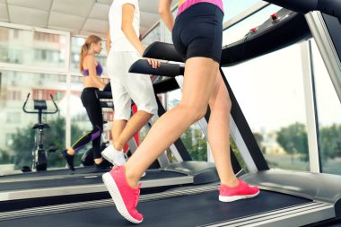 Spor salonunda, koşu bandı üzerinde çalışan gençler görünümü kapatın