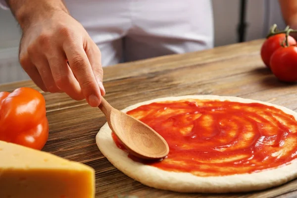 Uomo che applica la salsa di pomodoro sulla pizza — Foto Stock