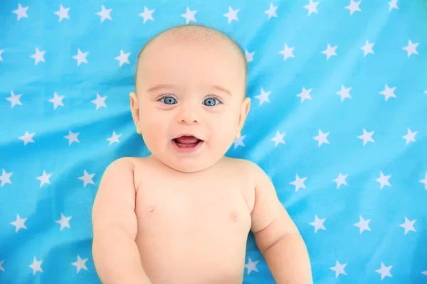 Bebê bonito deitado na colcha de cor — Fotografia de Stock