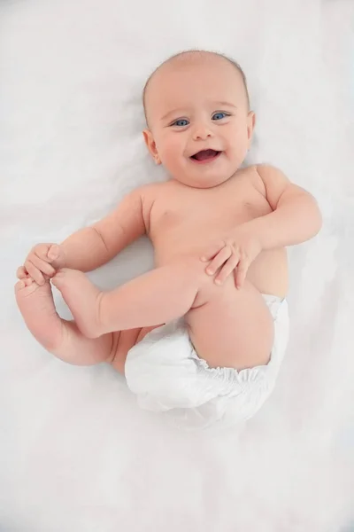 Cute baby lying on white bed sheet — Stock Photo, Image
