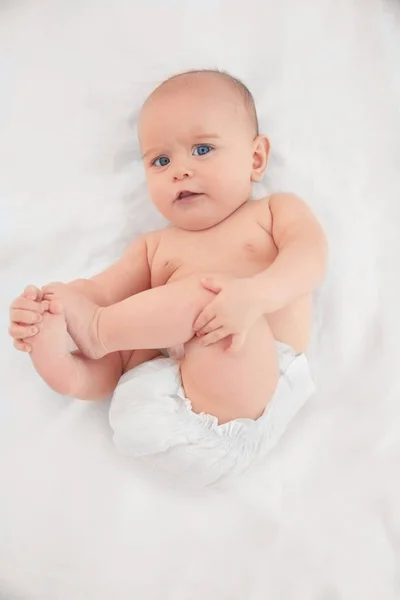 Aranyos baba fekvő fehér lepedő — Stock Fotó