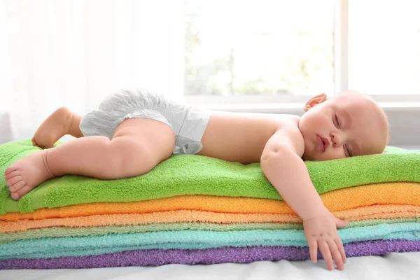 Cute baby sleeping on stack of colorful towels — Stock Photo, Image