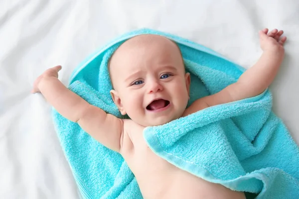 Söt baby med turkos handduk liggande på lakan — Stockfoto