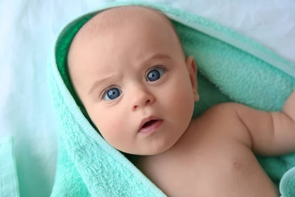 Bebê bonito com toalha turquesa deitada no lençol, vista de perto — Fotografia de Stock