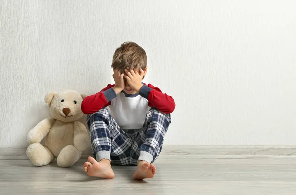 小男孩和泰迪熊在空房间的地板上哭泣 — 图库照片
