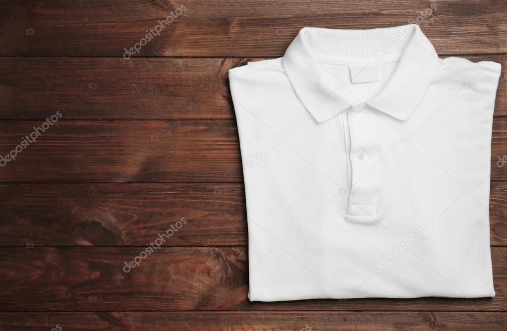 Blank white polo shirt on wooden background with place for text