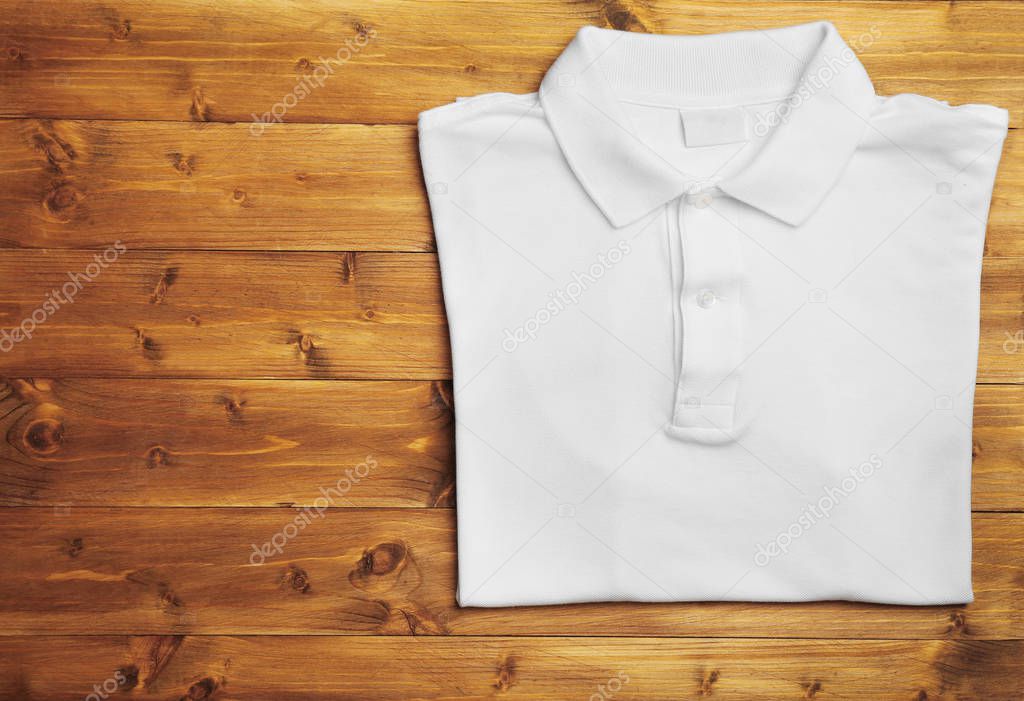 Blank white polo shirt on wooden background top view