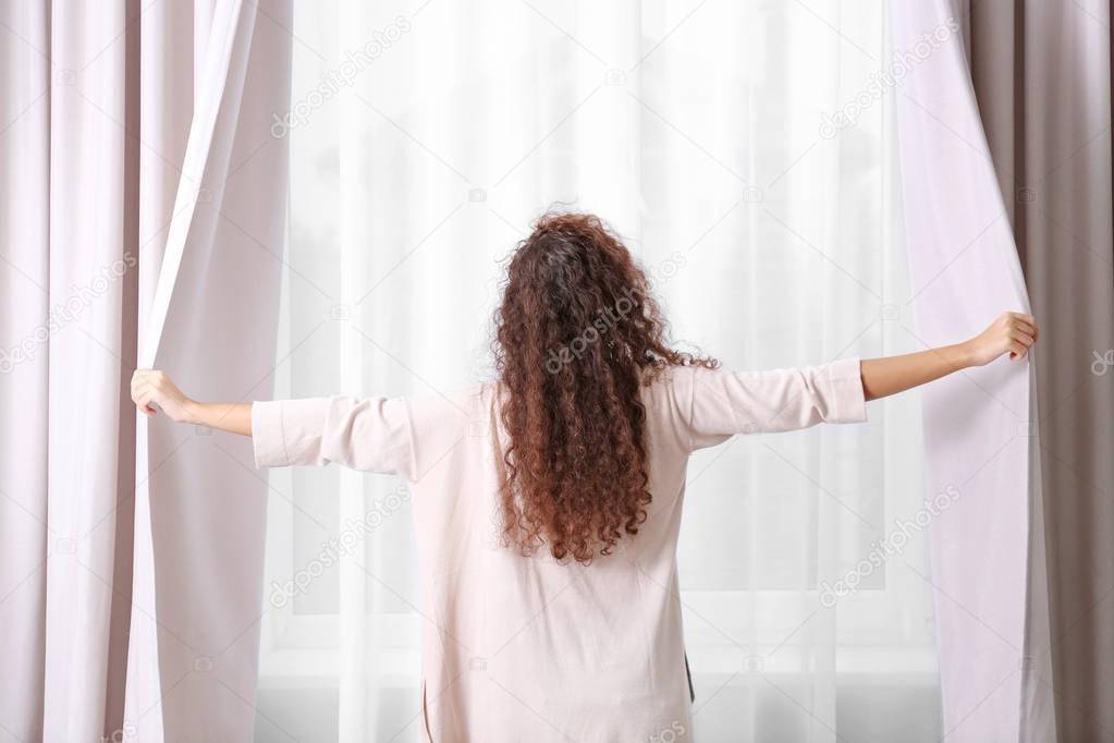 Woman opening curtains 