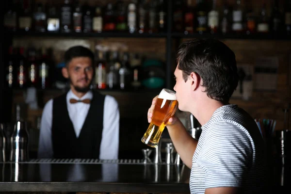 バーのカウンターでビールを飲む男性 — ストック写真