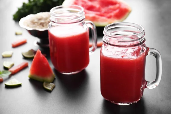 Jugs with smoothie, watermelon and lime slices — Stock Photo, Image