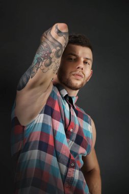 Koyu arka plan üzerinde poz genç dövmeli adam