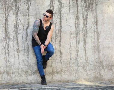 Genç dövmeli adam kirli beton duvar arka plan üzerinde poz