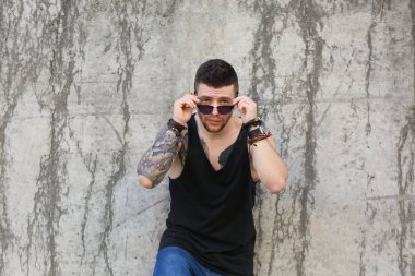 Genç dövmeli adam kirli beton duvar arka plan üzerinde poz