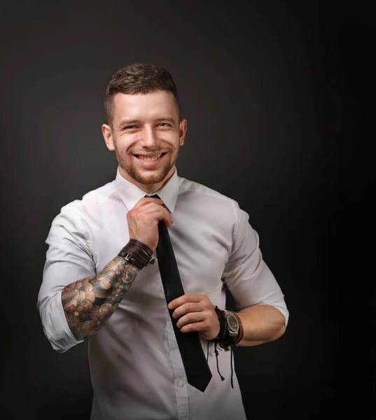 Young tattooed man posing on dark background — Stock Photo, Image