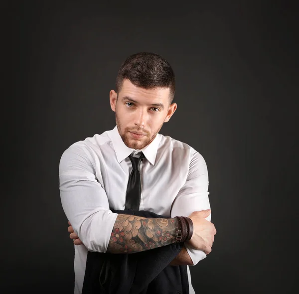 Joven hombre tatuado posando sobre fondo oscuro —  Fotos de Stock