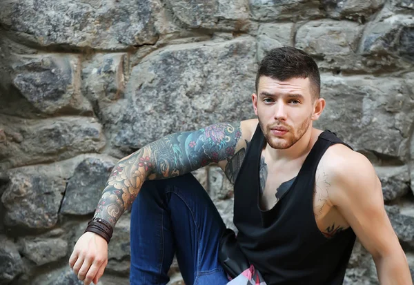 Jovem Tatuado Homem Posando Pedra Parede Fundo — Fotografia de Stock