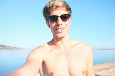 Yakışıklı adam kumsalda selfie alarak güneş gözlüğü