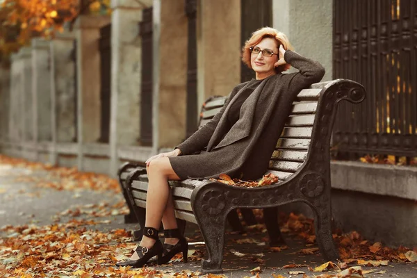 Mulher sentada no banco no parque de outono — Fotografia de Stock