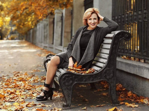 Mujer sentada en el banco en el parque de otoño —  Fotos de Stock