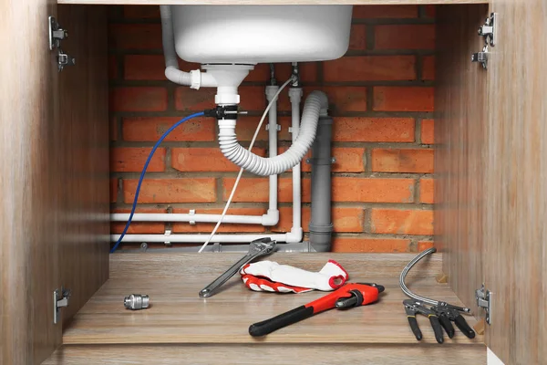 Loodgieter tools en handschoenen onder gootsteen, close-up — Stockfoto