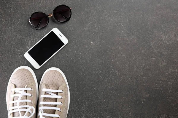 Серая обувь, солнцезащитные очки и мобильный телефон — стоковое фото