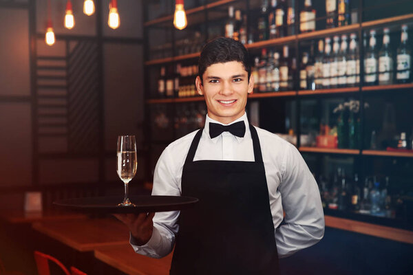 Мужчина официант держит поднос с шампанским

