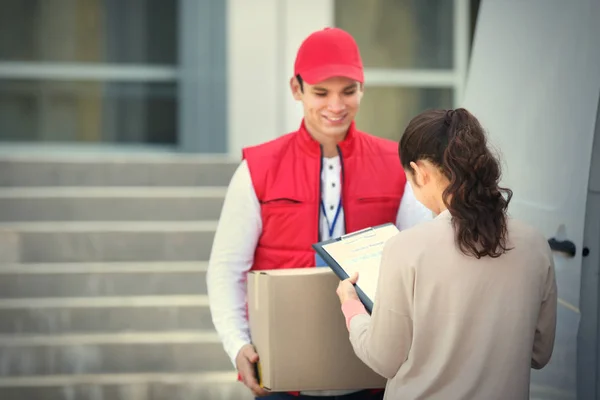 若い女性が男性の宅配便から小包を提供するための領収書を署名 — ストック写真