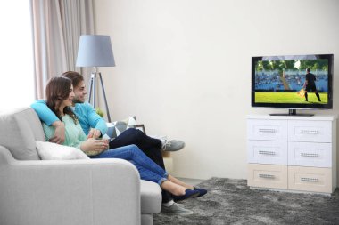 Genç bir çift futbol oyunu evde televizyon izliyor. Boş zaman ve eğlence kavramı.