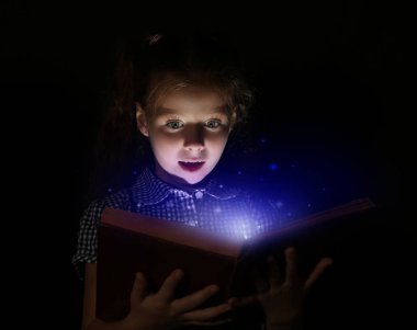 Sevimli kız gece kitap okumak. Sihirli ışık kitaptan geliyor.