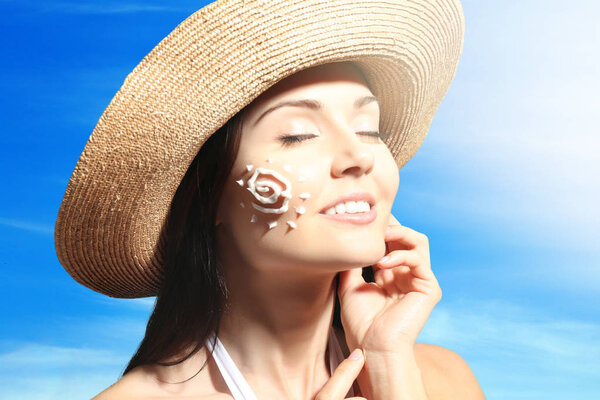 Женщина с солнцезащитным кремом в форме солнца на лице. Концепция ухода за кожей
.