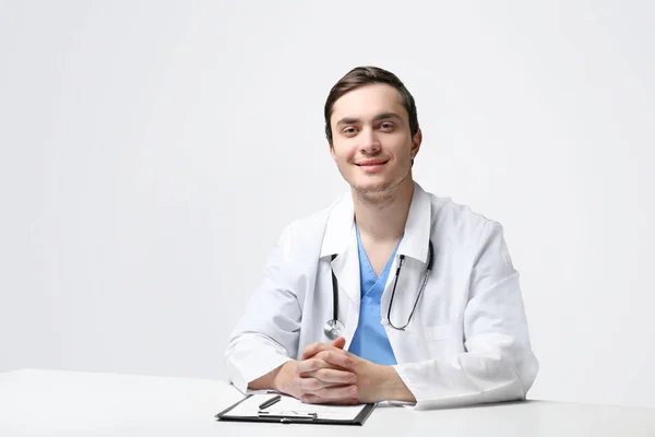 Junger Arzt sitzt am Tisch — Stockfoto