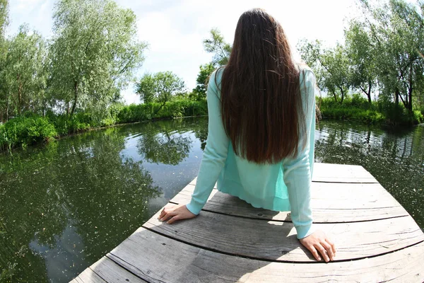 Mujer sentada en el muelle de madera — Foto de Stock